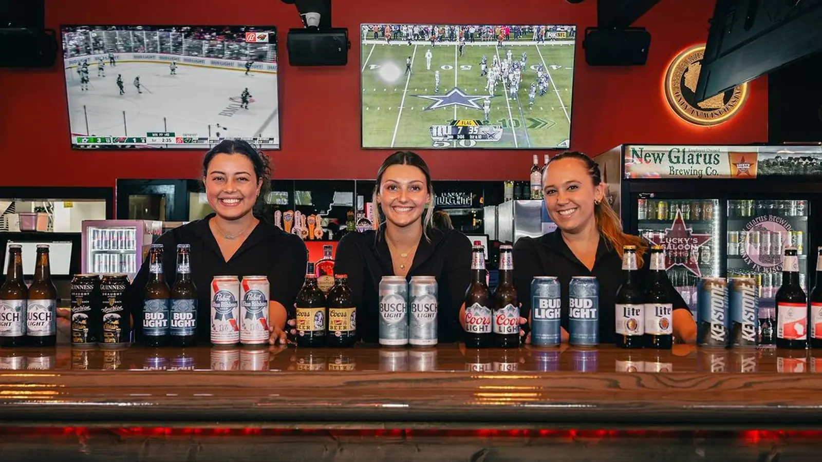 Lucky’s Saloon staff holding up a lineup of cold beers